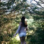 Photo of girl in stand of trees. Titled "A Long Way Home" by Briana Eckert