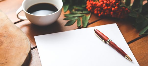 a red pen on a blank sheet of paper on a wooden desk