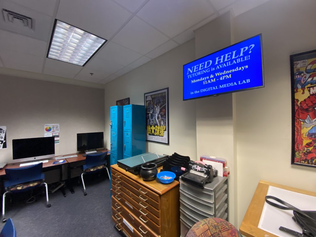 A small television display highlights important announcements and events for Digital Media students.