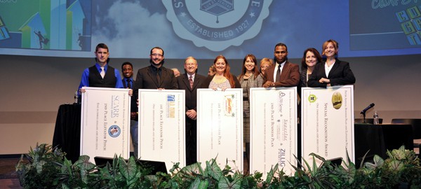 Business Competition winners up on stage holding checks