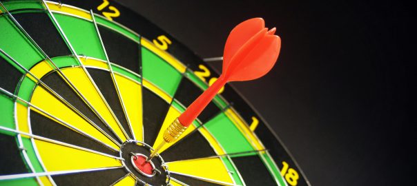 A red dart hits dead center on a dart board.