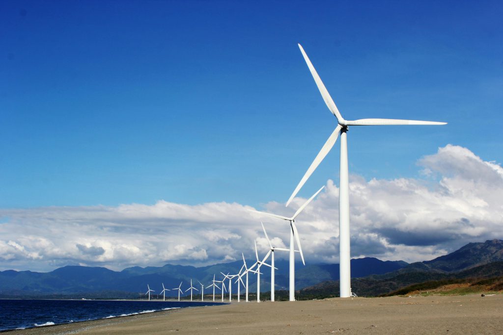 Line of wind turbines along a beach.