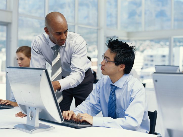 Two men in an office looking at a computer together
