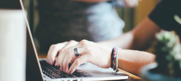 Hands typing on a laptop keyboard.
