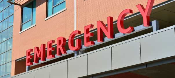 Red sign over a hospital entrance that reads emergency