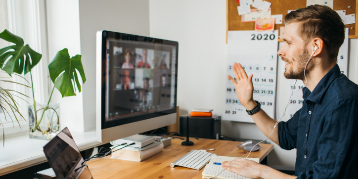 Man waving while having video meeting at home from his desk.