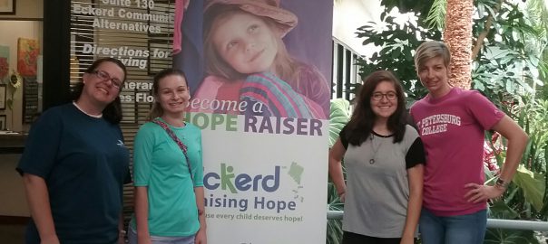 Four women standing in front of poster for Eckerd Kids - Raising Hope Program with Women on the Way