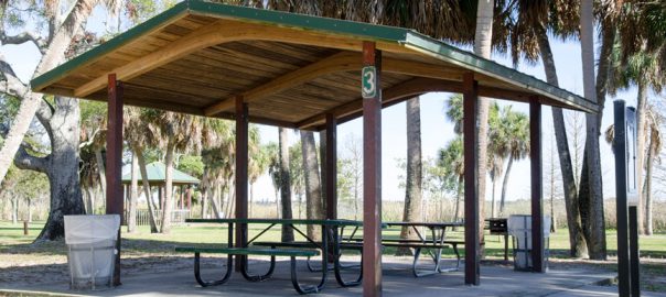 A wooden awning covers an area with picnic tables.