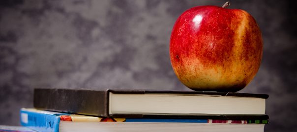 An apple sitting on top of books.