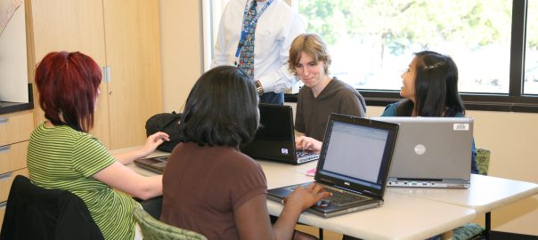 A man instructs a group of learners at computers
