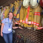 Student standing in front of fire fighter jackets