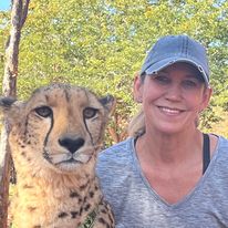 woman sits closely with a cheetah