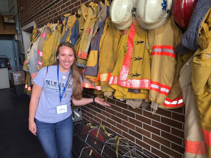 Student standing in front of fire fighter jackets