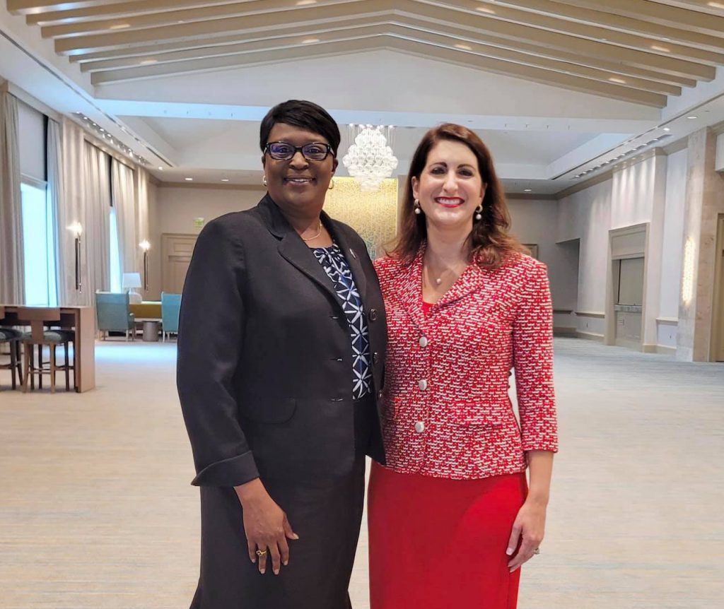 SPC President Dr. Tonjua Willams and Dr. Angela Garcia Falconetti, President of Polk State College and Chair of FCS Council of Presidents pose standing next to each in a conference room.