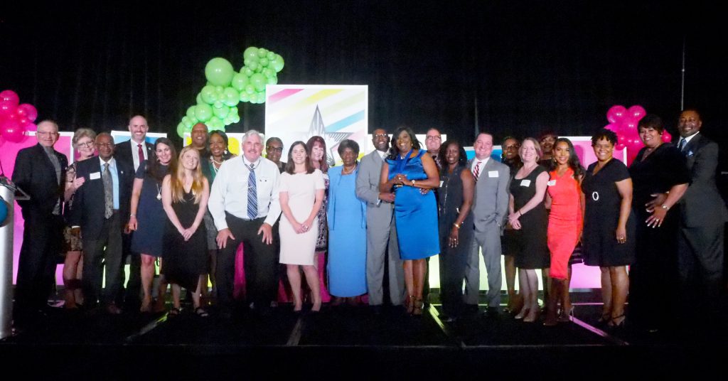 Dr. Williams stands with friends, family, and SPC employees on a large stage after being inducted into the Tampa Bay Business Hall of Fame.