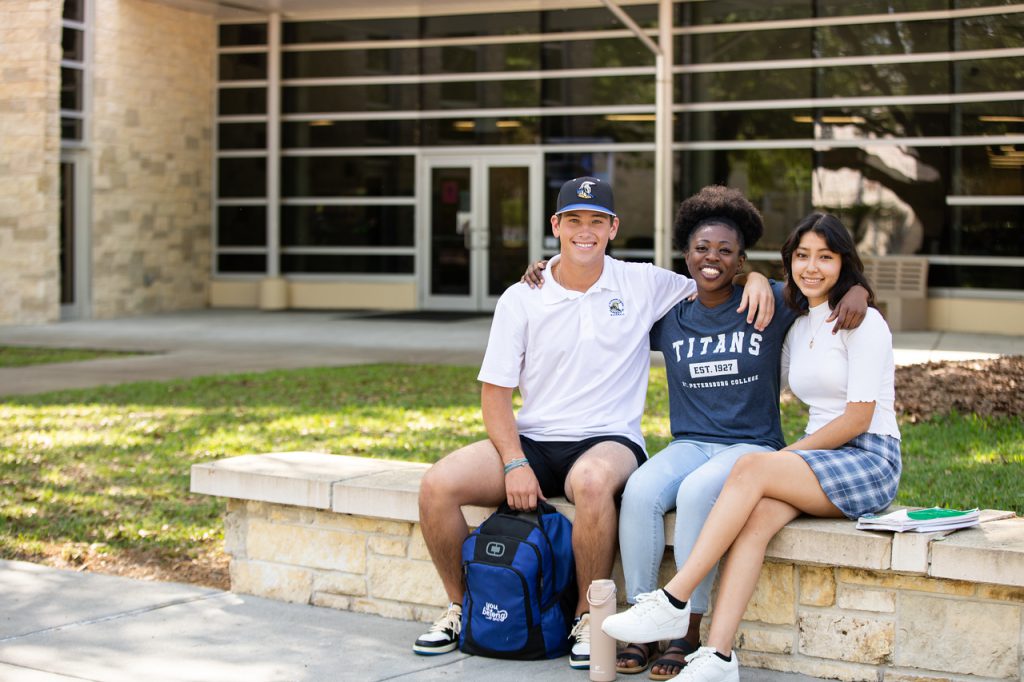 three students sit on a bench outside on the Gibbs campus