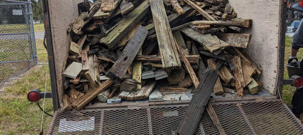 flatbed trailer, loading gate in the down position. Trailer is nearly full with sections of lumber gathered from around the STEM Center shoreline.