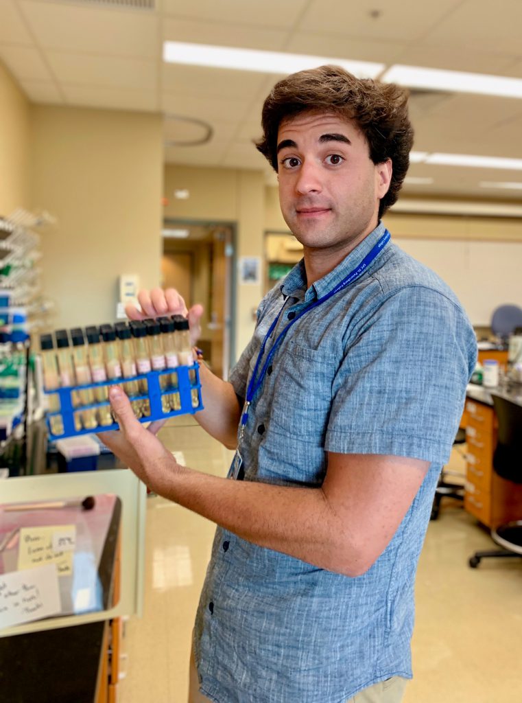 Robinson in lab, holding a tray of test tubes