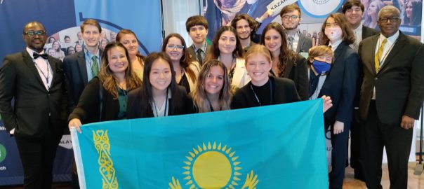 Model UN members stand behind a teal and yellow colored flag